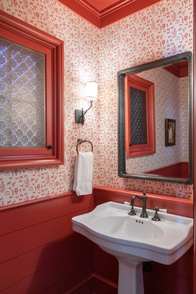 a mostly red powder room with a patterned wallpaper