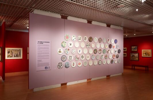 lilac colored wall in gallery with mounted plates