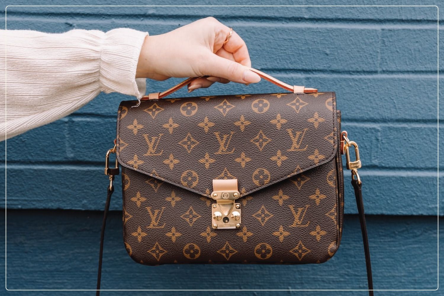 woman's hand holding out louis vuitton purse