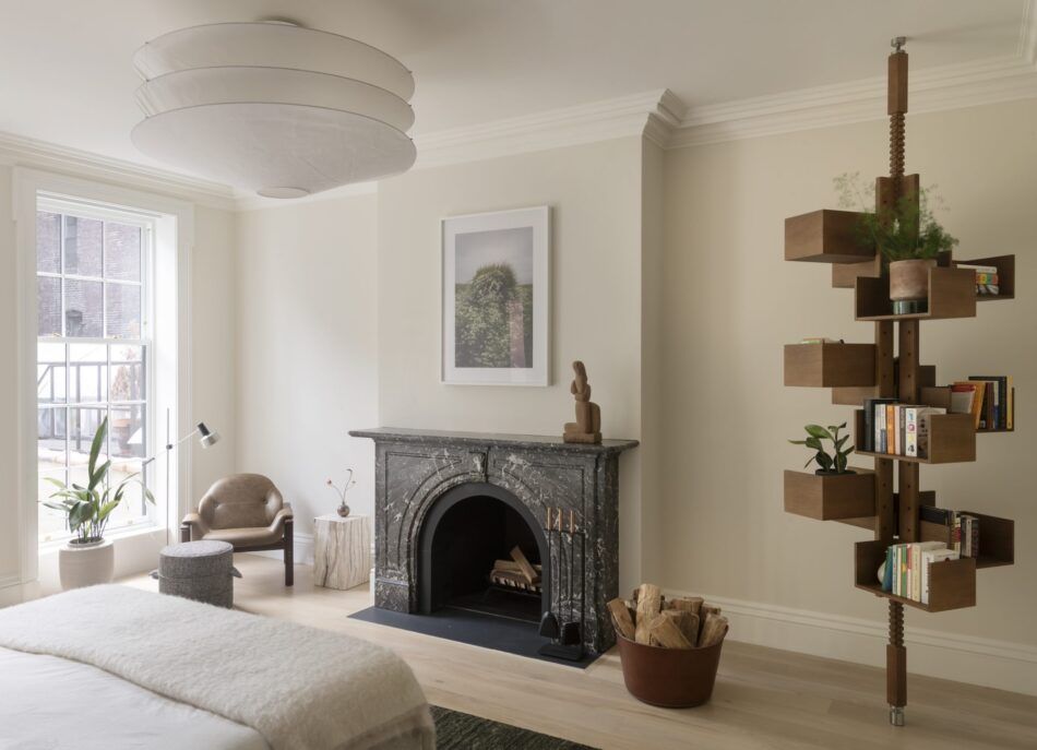 In the primary bedroom of a Greenwich Village townhouse by Elizabeth Roberts, a Gianfranco Frattini tension-mounted bookshelf mingles with a three-tiered Ingo Maurer ceiling light.