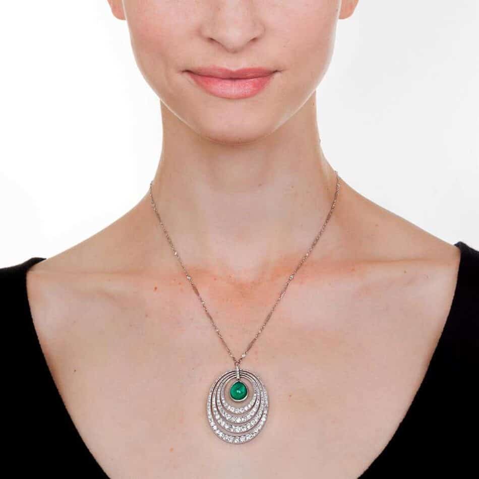 woman wearing an Art Deco emerald and diamond pendant necklace