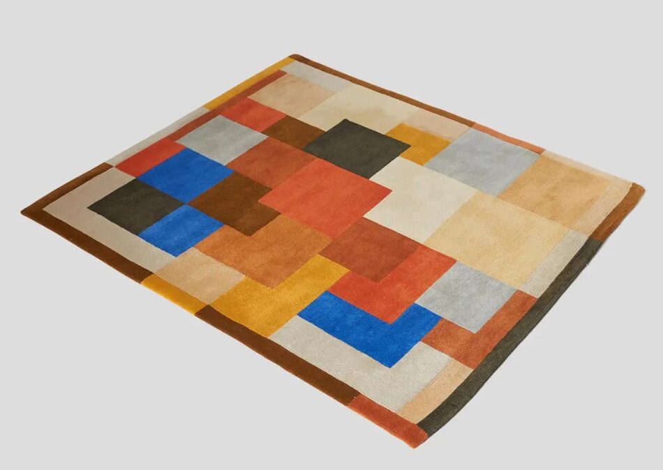 Sonia Delaunay Rug with a pattern of overlapping squares and rectangles in shades of blue, red, tan, cream, brown gray and black.