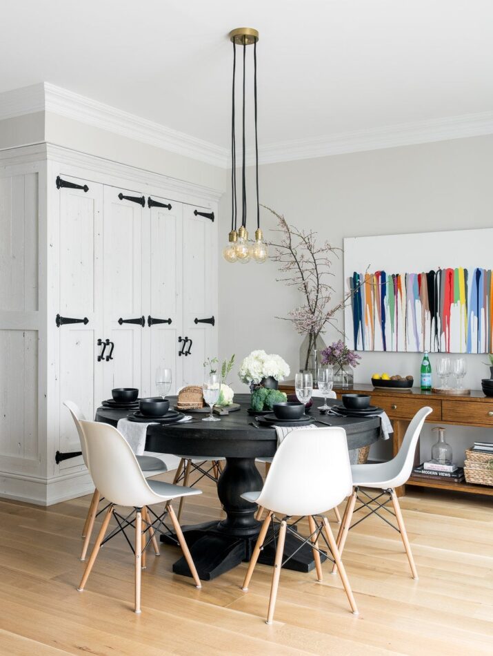 a small dining space with a black table and white dining chairs