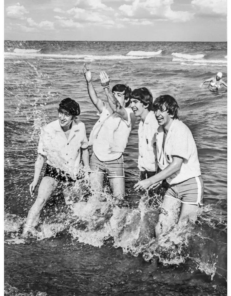 The Beatles splashing around in the ocean in 1964 by Lynn Goldsmith.