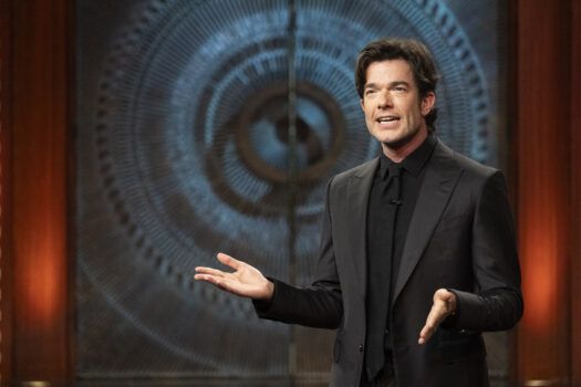 John Mulaney in front of Brutalist doors