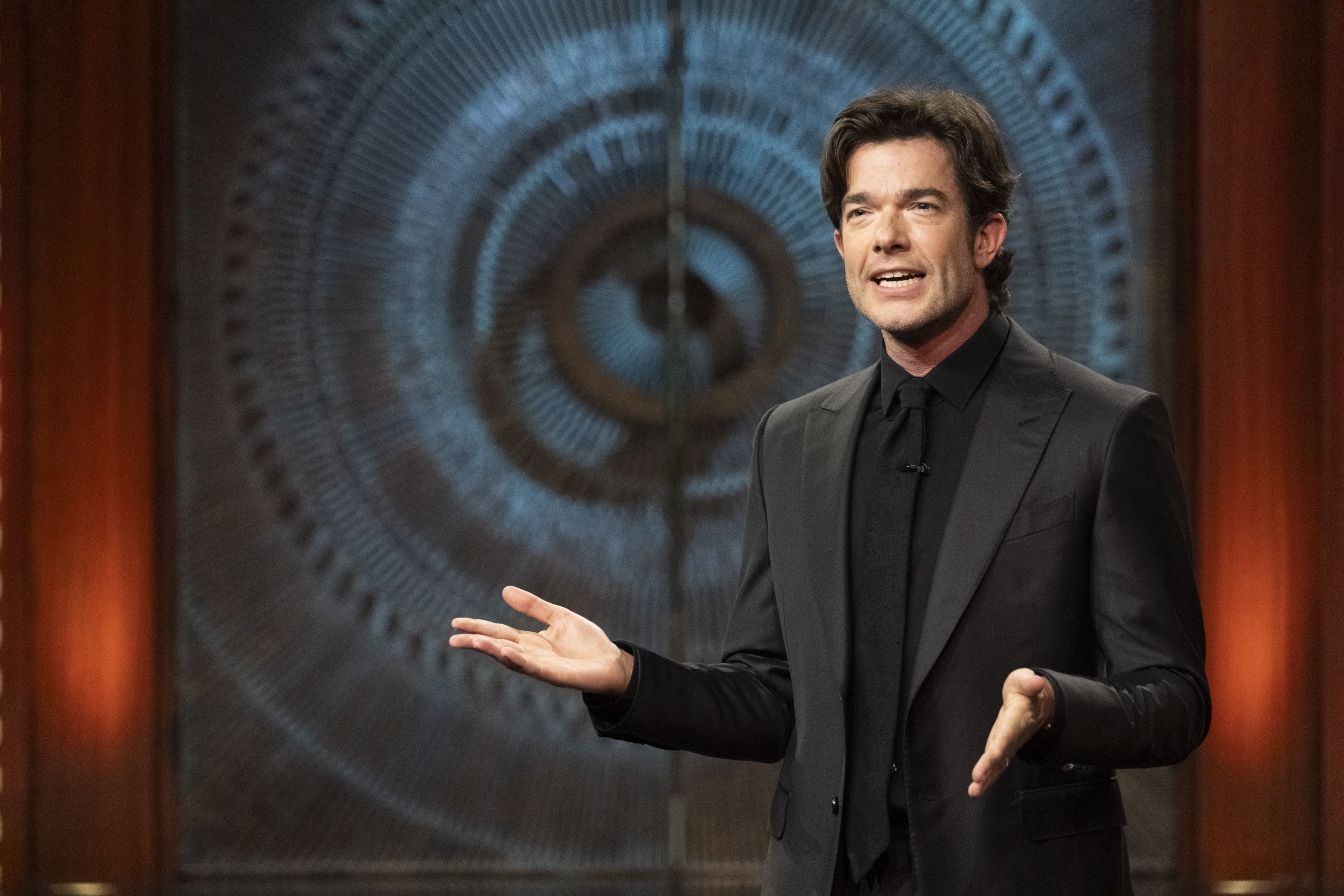 John Mulaney in front of Brutalist doors