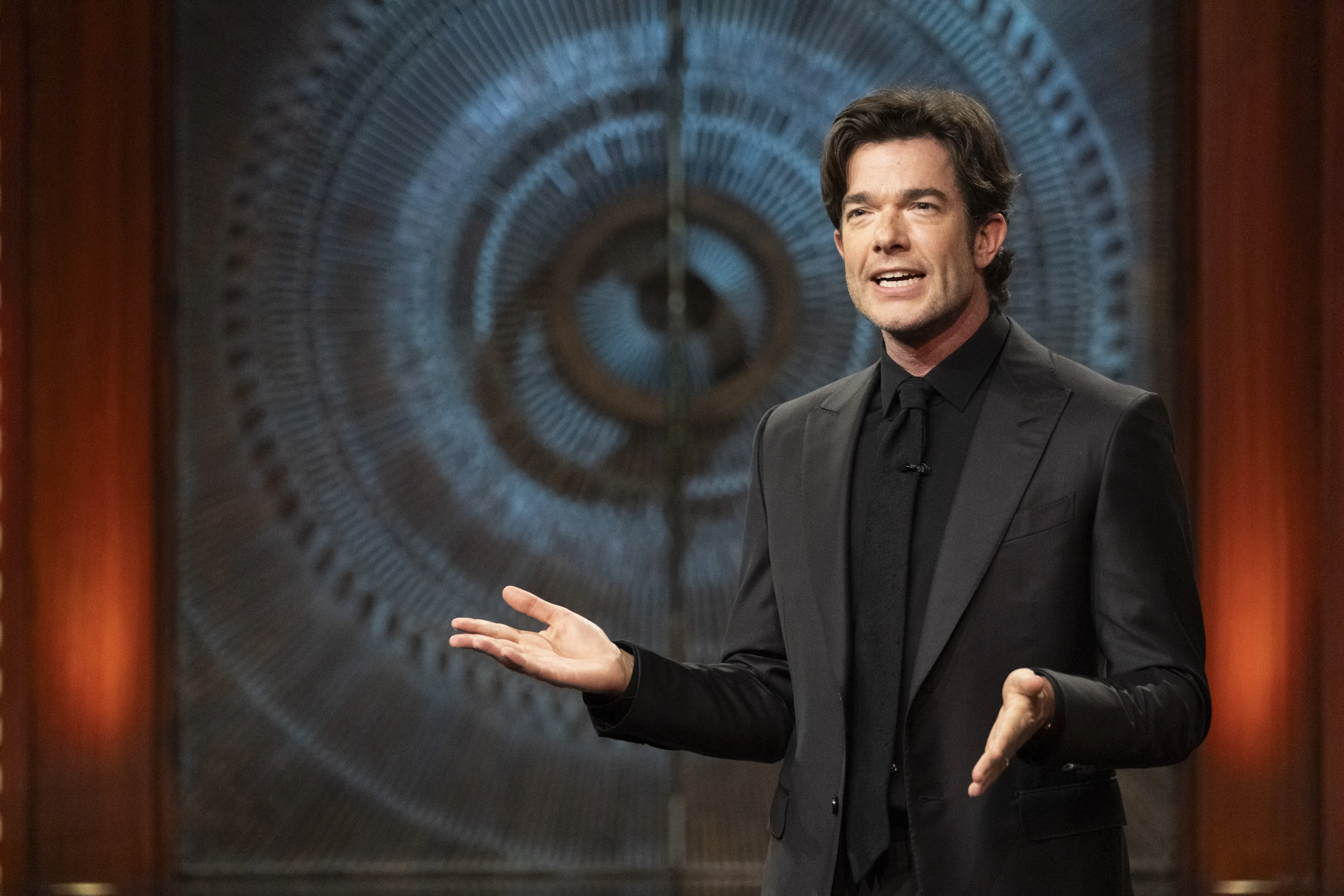 John Mulaney in front of Brutalist doors