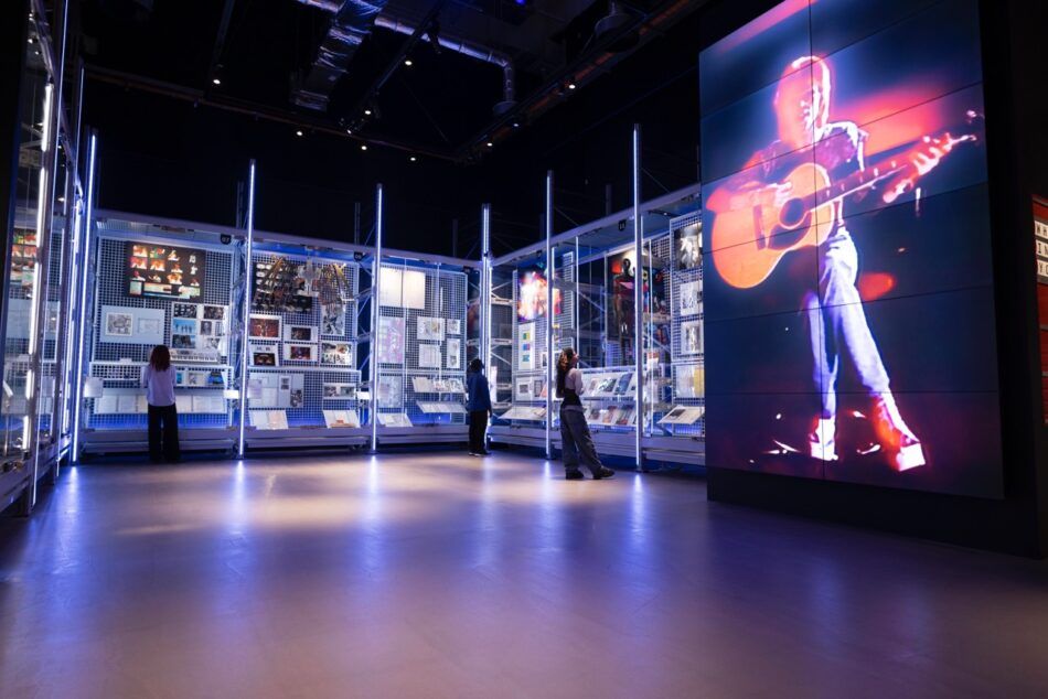 Displays present different objects and ephemera from the David Bowie Centre alongside a large screen that shows footage of the musician performing