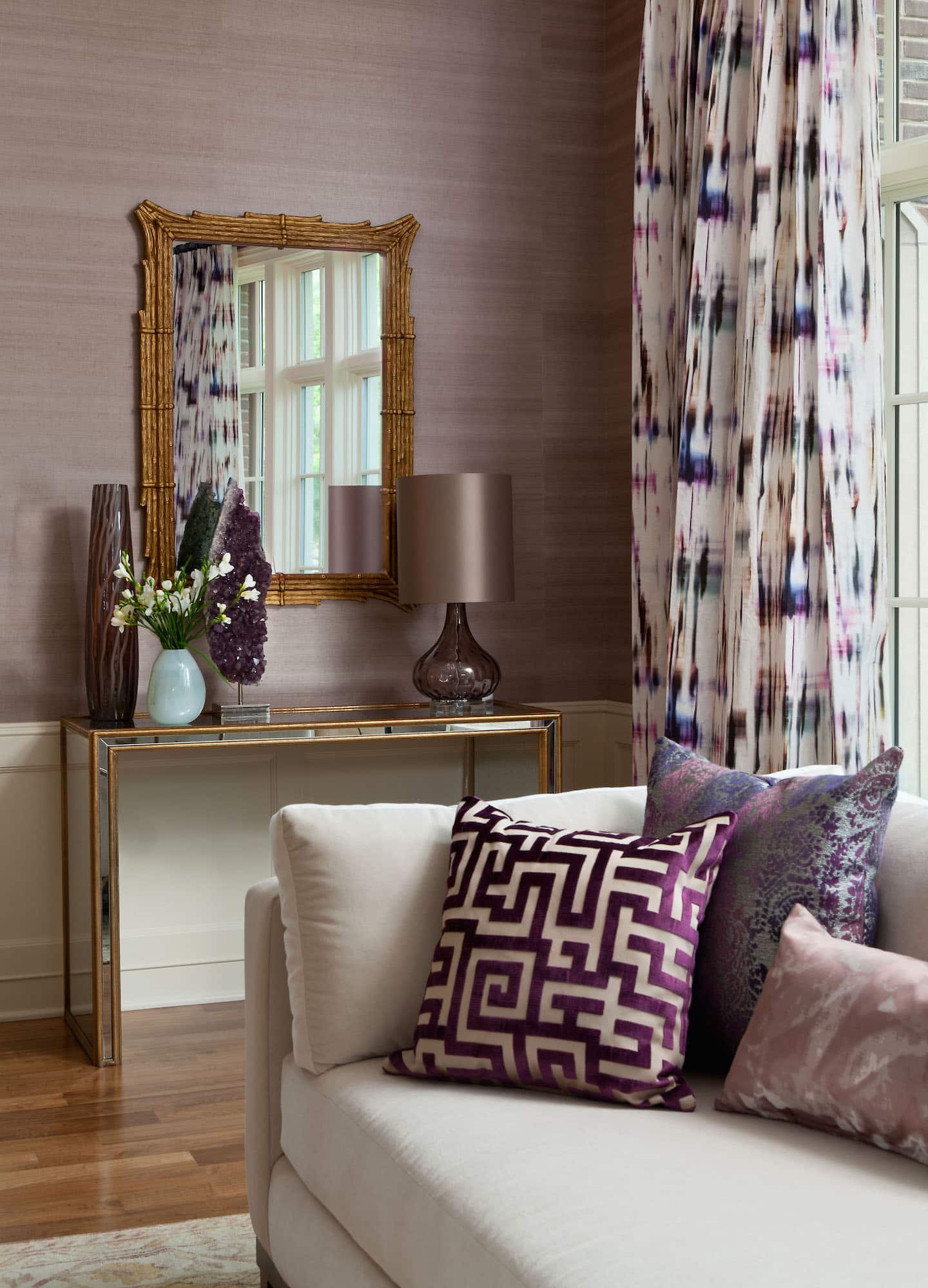 In a living room designed by Andrea Schumacher, Romo’s Black Edition Cromatico drapery fabric in violet mingles with lavender grasscloth wallpaper from Kneedler Fauchère and throw pillows in various fabrics. Photo by Emily Minton Redfield