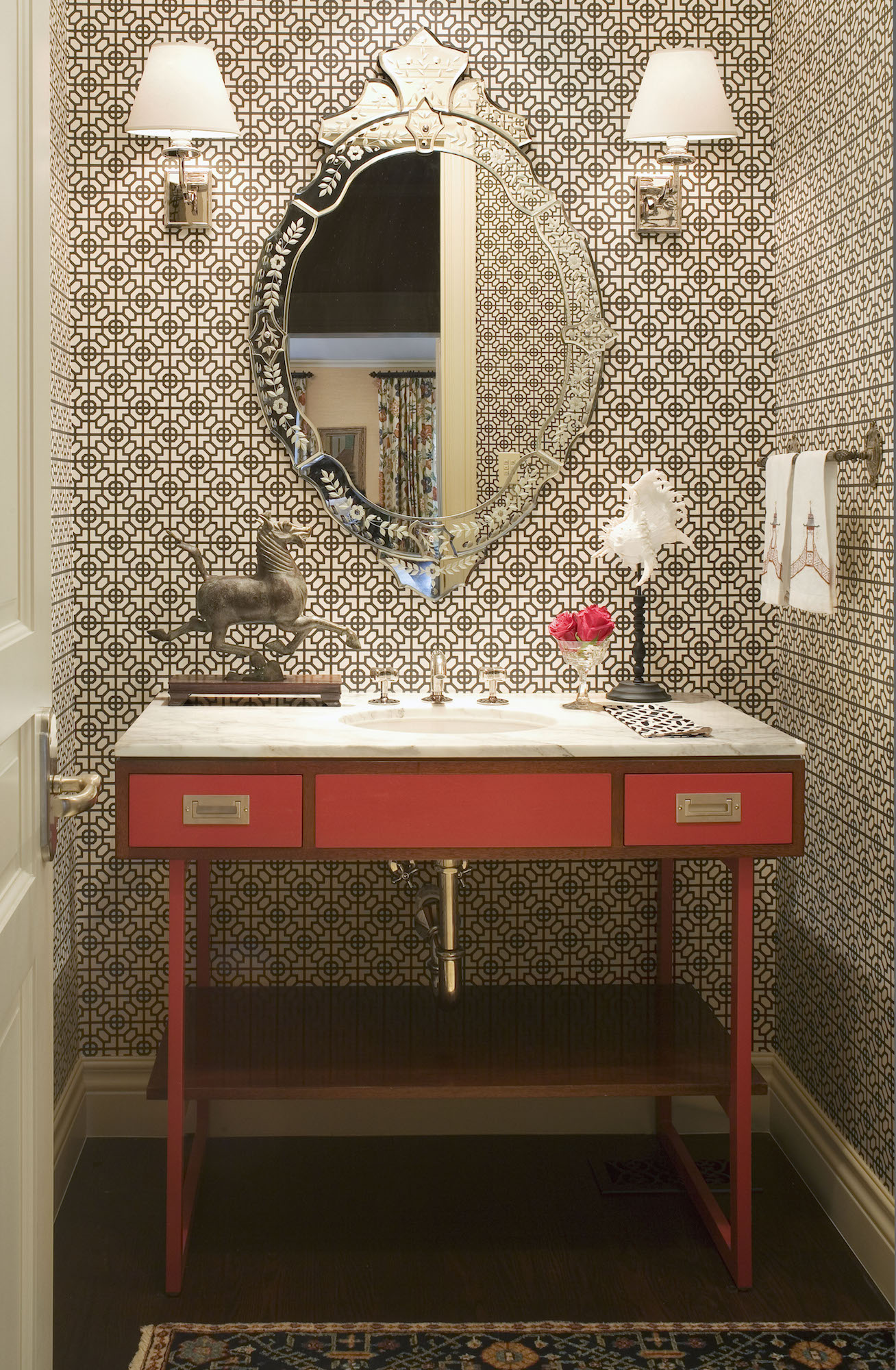 Andrea Schumacher transformed a petite powder room into a statement-making space with a vibrant red vanity from Waterworks and Sussex wallpaper in black and white by Designers Guild. Photo by Emily Minton Redfield
