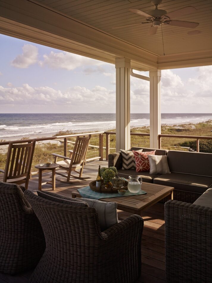 a patio with rocking chairs and a beach view