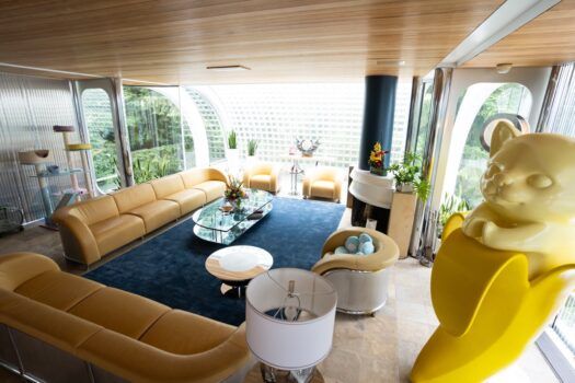 A living room with curved chrome furniture and a yellow sculpture of a bear inside of a banana