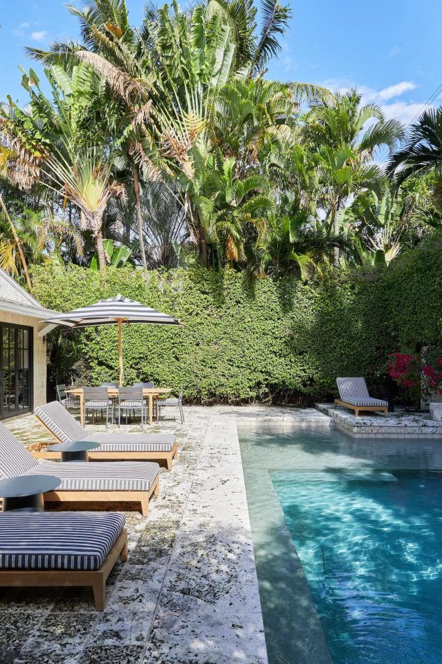 A bungalow by Grisoro Studio embraces the laidback glamour of Miami Beach while honoring the property’s history. The sleek pool is enclosed by tall palms and dense hedges.