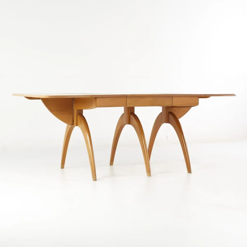 A wooden Haywood Wakefield wishbone dining table with six curved legs against a white backdrop.