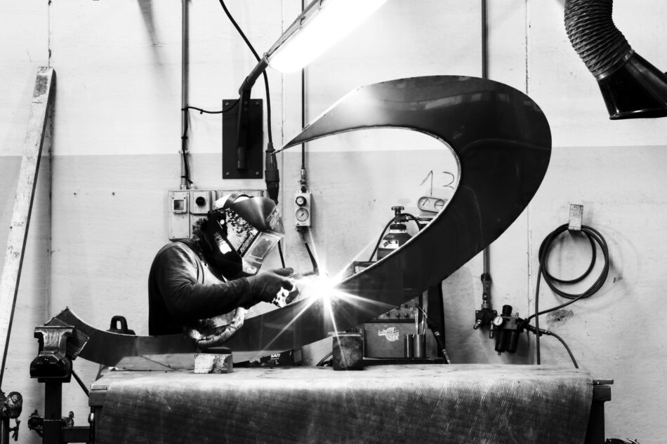 A black and white photo of a welder working on the table's base