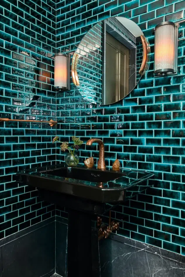 a dark green powder room with subway tiled walls