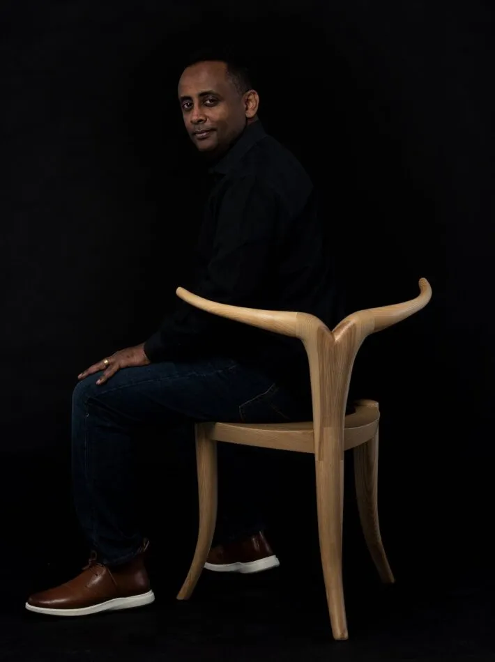Furniture designer Jomo Tariku sitting in his Nyala chair