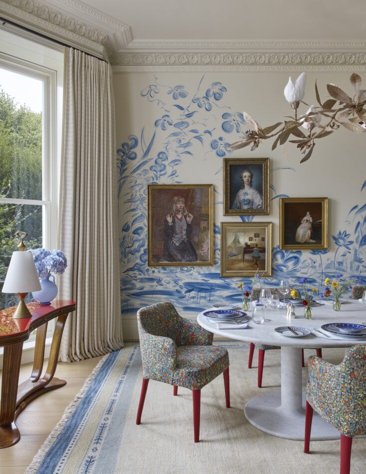 Bryan O'Sullivan-designed dining room in London's Notting Hill, with four female portraits on a mural wall.