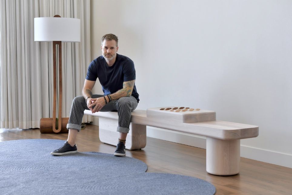 Last Ditch Design founder Todd Hewitt sits on his Nostromo bench with the Silas floor lamp behind him