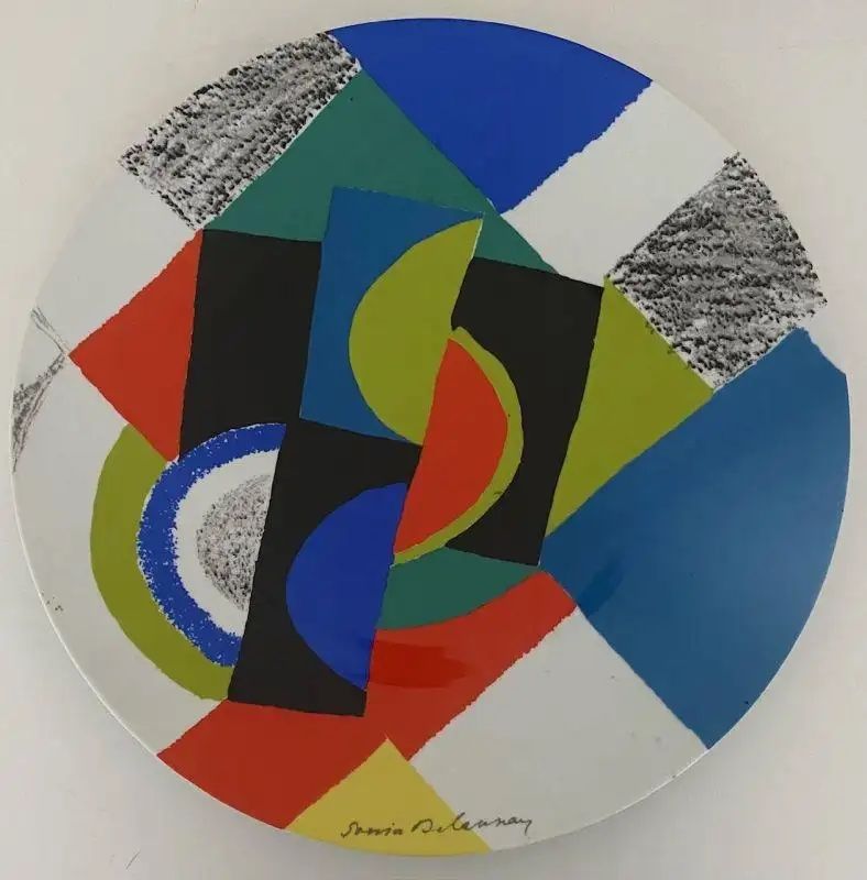 A ca. 1980 white porcelain plate by Sonia Delaunay with an abstract design in red, lime green, blue and black