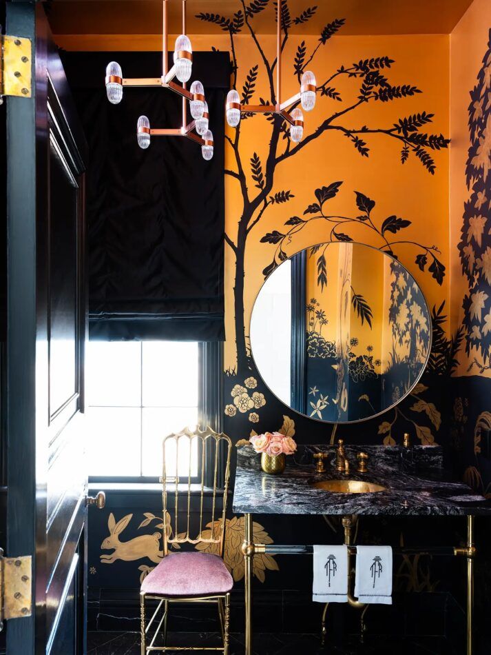 A hand-painted chinoiserie mural by Penshaw Hill envelops an Atlanta powder room room in black and gold, in a 1930s house revamped by Melanie Turner. 