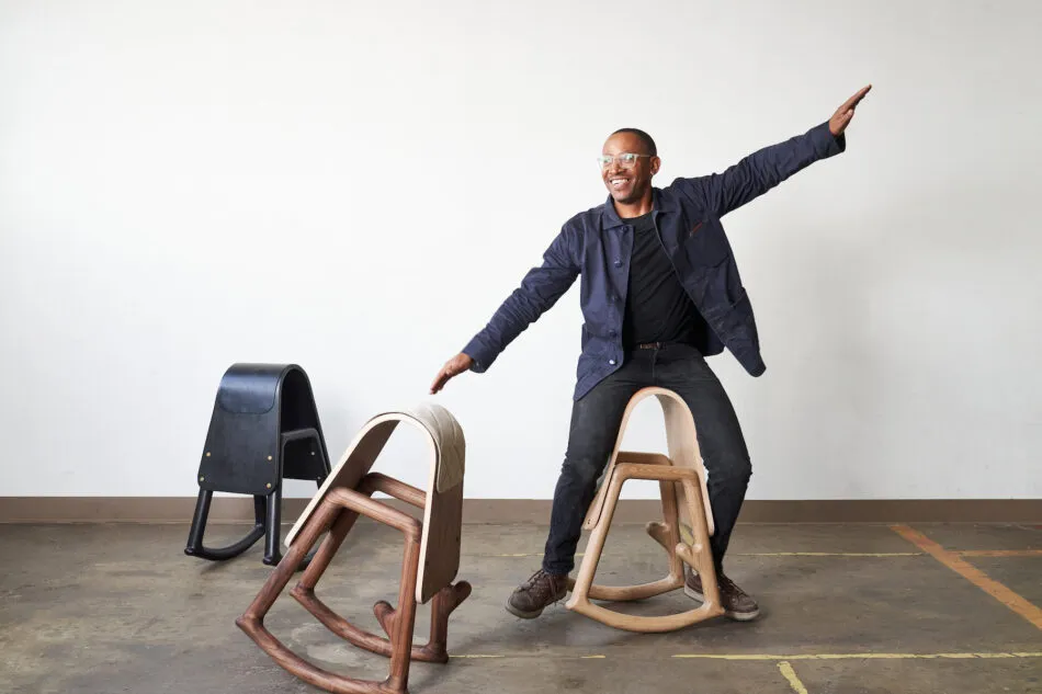 Furniture designer Norman Teague balances on one of his Sinmi rocking stools