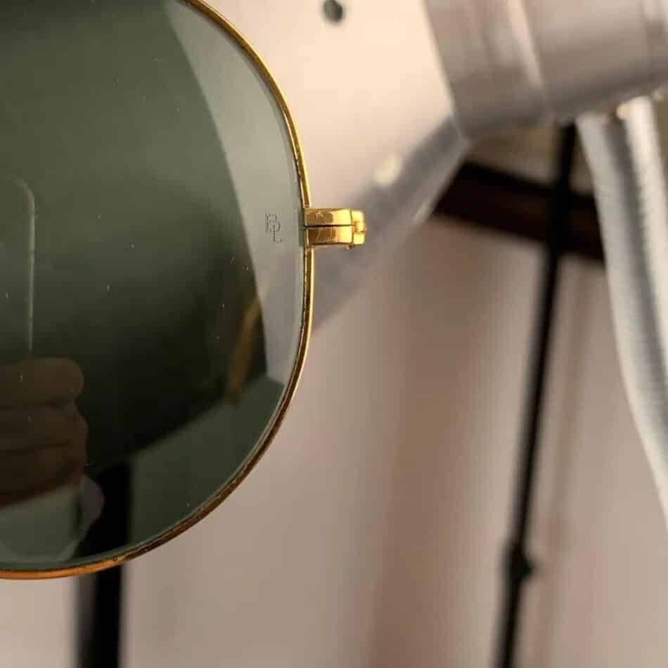 The letters BL etched into the left lens of The Ray-Ban signature logo on the left lens of a pair of late-20th-century Outdoorsman sunglasses offered by Opherty & Ciocci