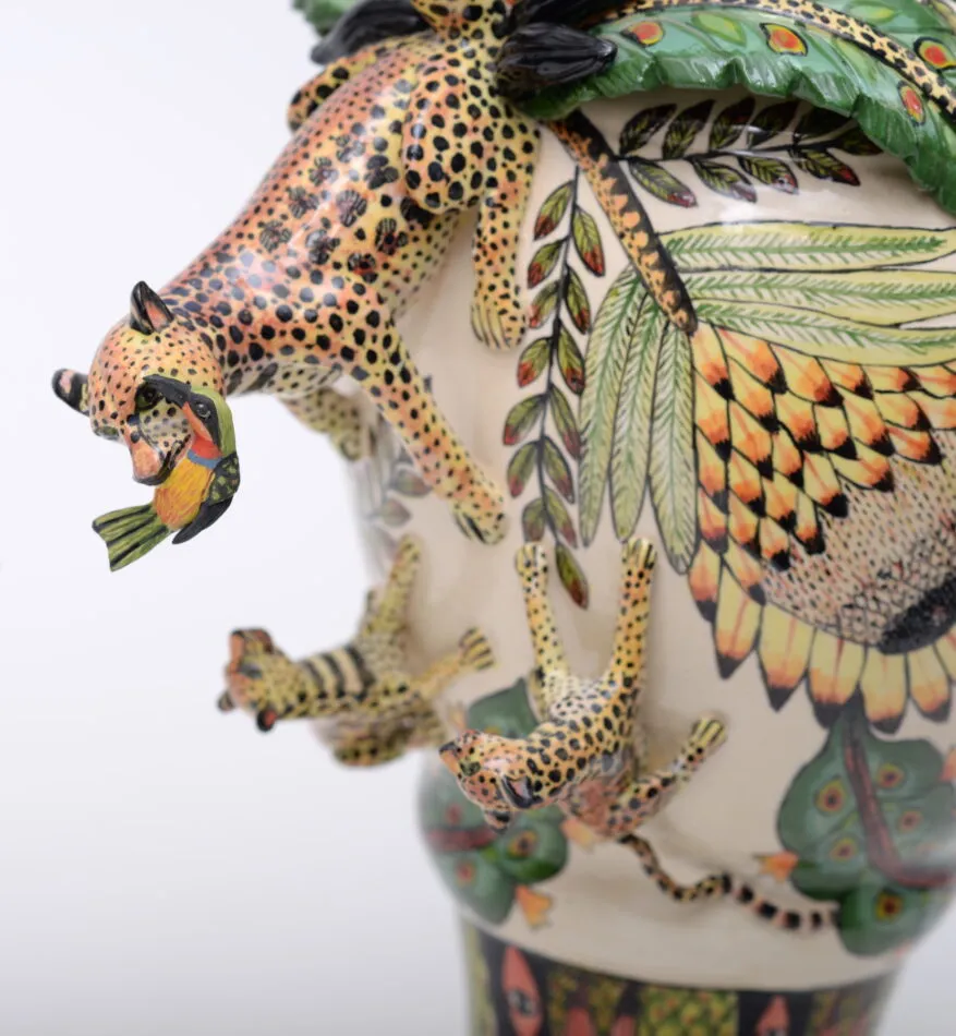 A closeup of a leopard vase by Ardmore Design showing a leopard on the side of the vase with a colorful bird in its mouth