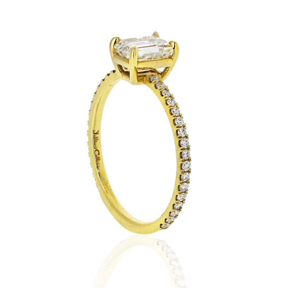 A yellow gold emerald-cut diamond engagement ring with micro-pavé diamonds on the sides