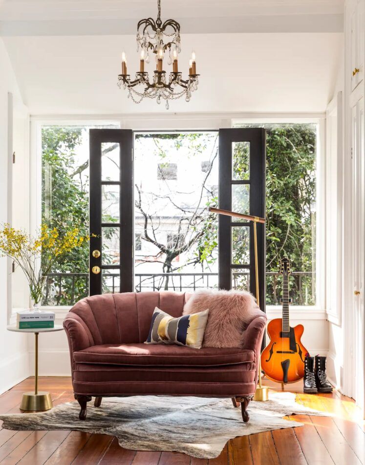 The primary suite of a Savannah townhouse reworked by Ashton Taylor has an antique velvet settee and a balcony whose doors are now framed in plate glass.