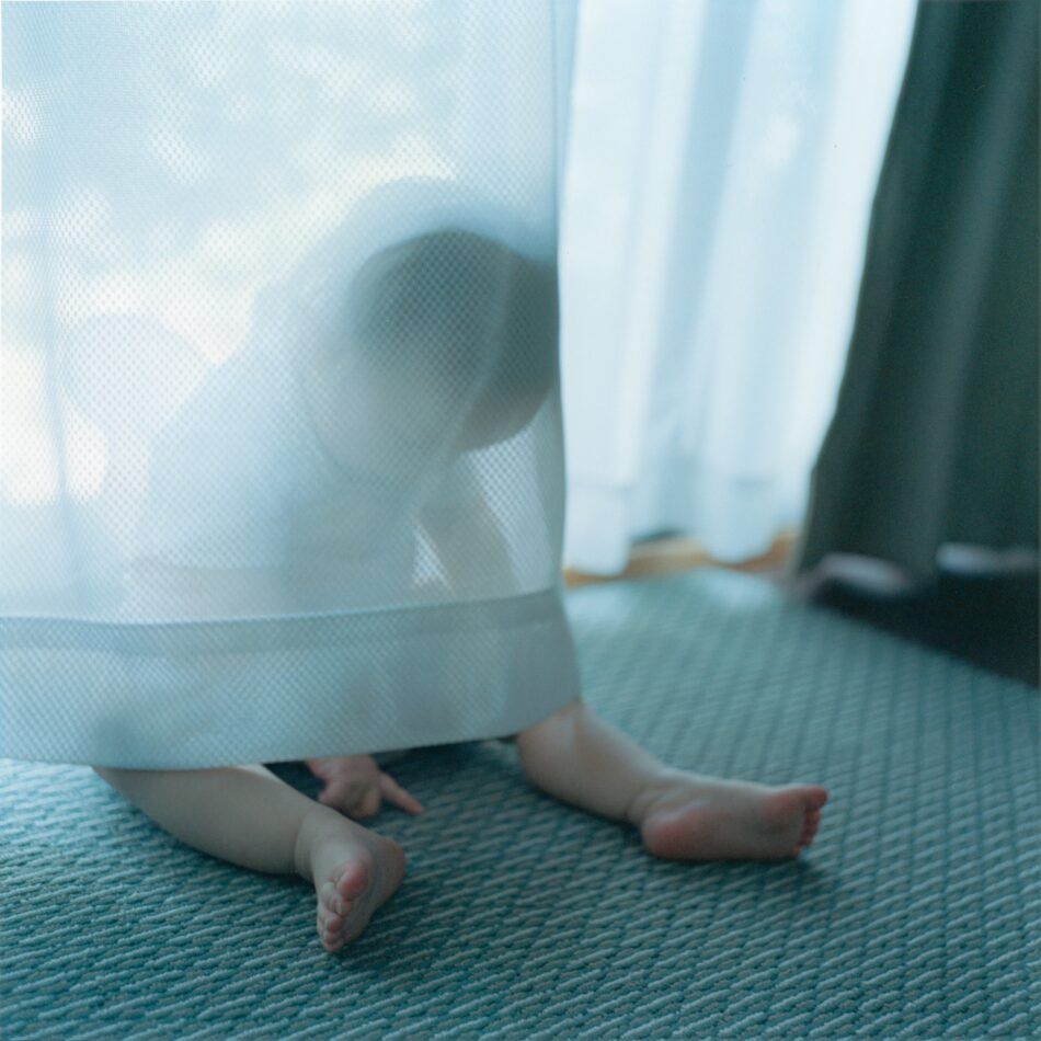 Rinko Kawauchi: Untitled portrait of her baby playing behind a curtain, 2012, from the series "An interlinking"