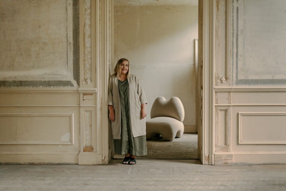 Furniture designer Victoria Yakusha standing in a doorway with her Donna chair in the room behind her