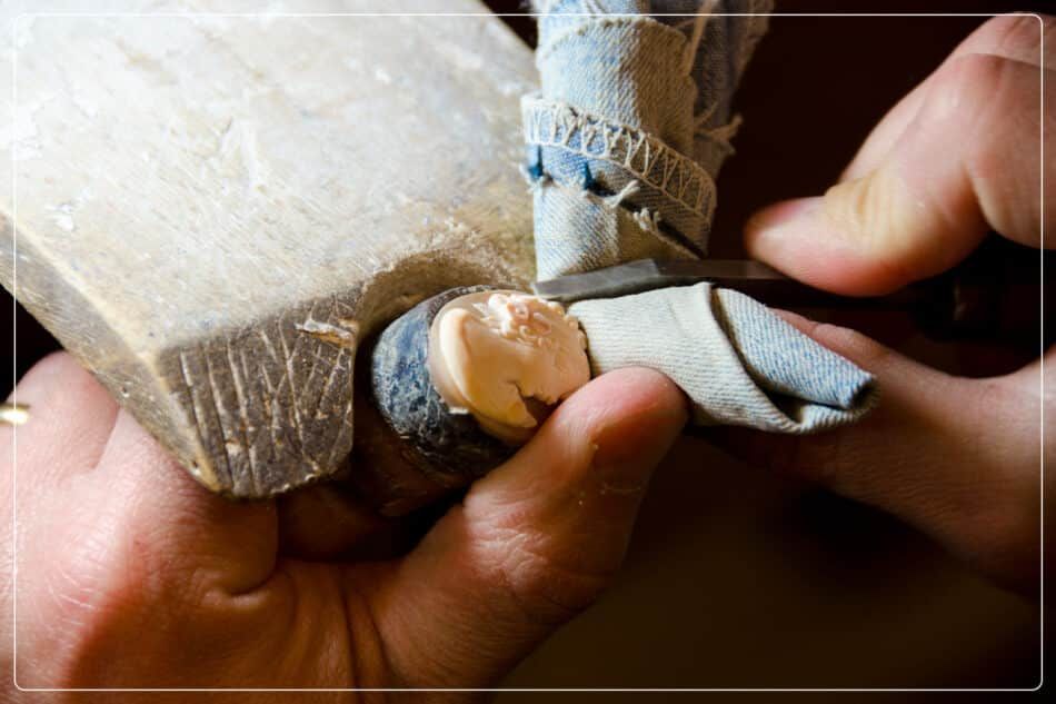 A close-up of an artisan carving a cameo with a specialized tool.