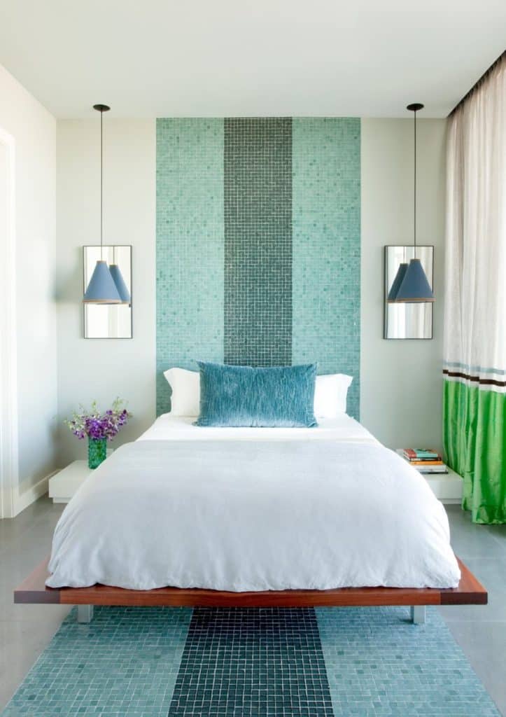 A bedroom in this Frank Roop–designed Miami Beach apartment has swimming pool-style tiles that extend from the floor up to the ceiling.