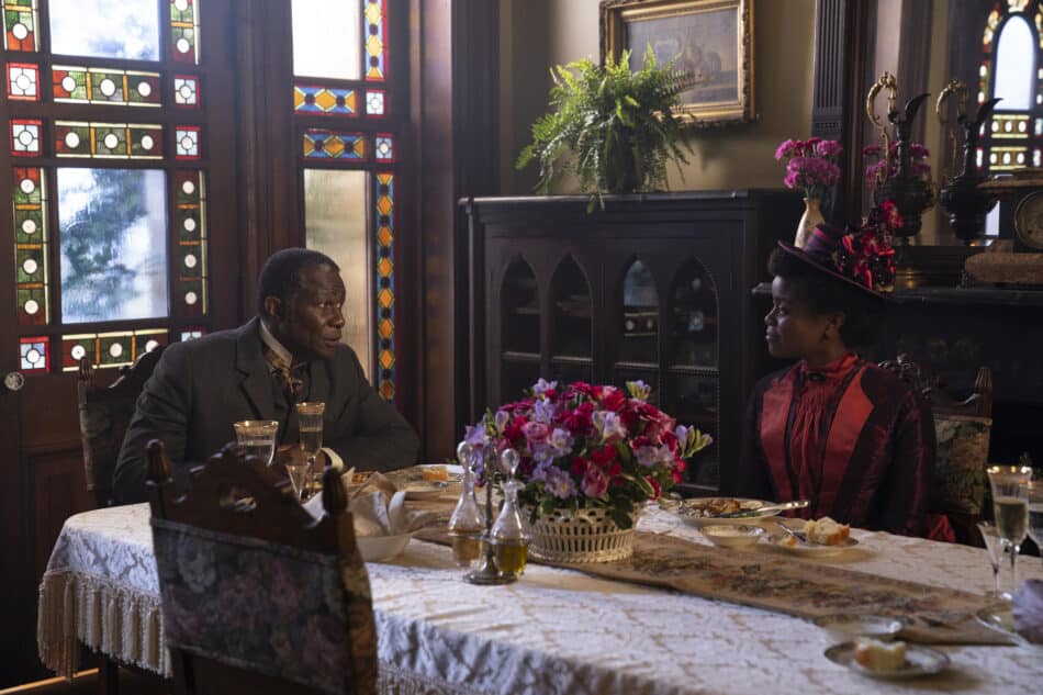 A still depicting a house in Troy, New York where Mr. Scott (John Douglas Thompson) and his daughter, Peggy (Denée Benton), sit on carved-oak chairs around a damask-covered dining table.