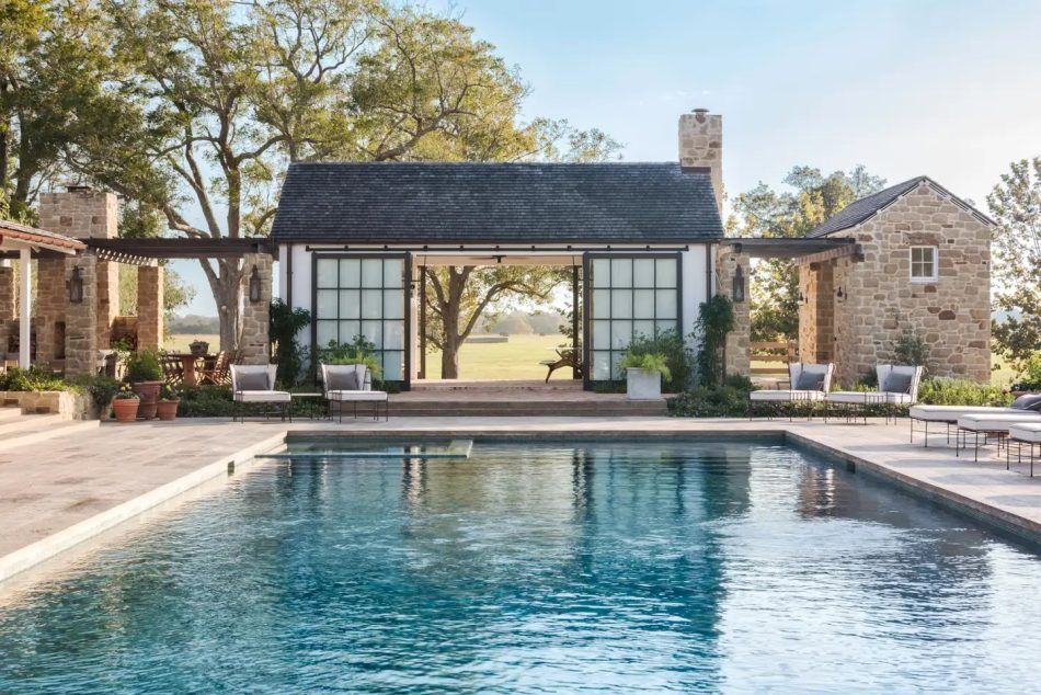 Outside Houston, a family home by Fern Santini was designed for playful afternoons and large-scale entertaining. The pool sits beside brick patios and outbuildings by architect Michael G. Imber.