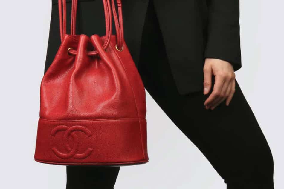 A photo of a person holding a Chanel red caviar-leather Bucket bag.
