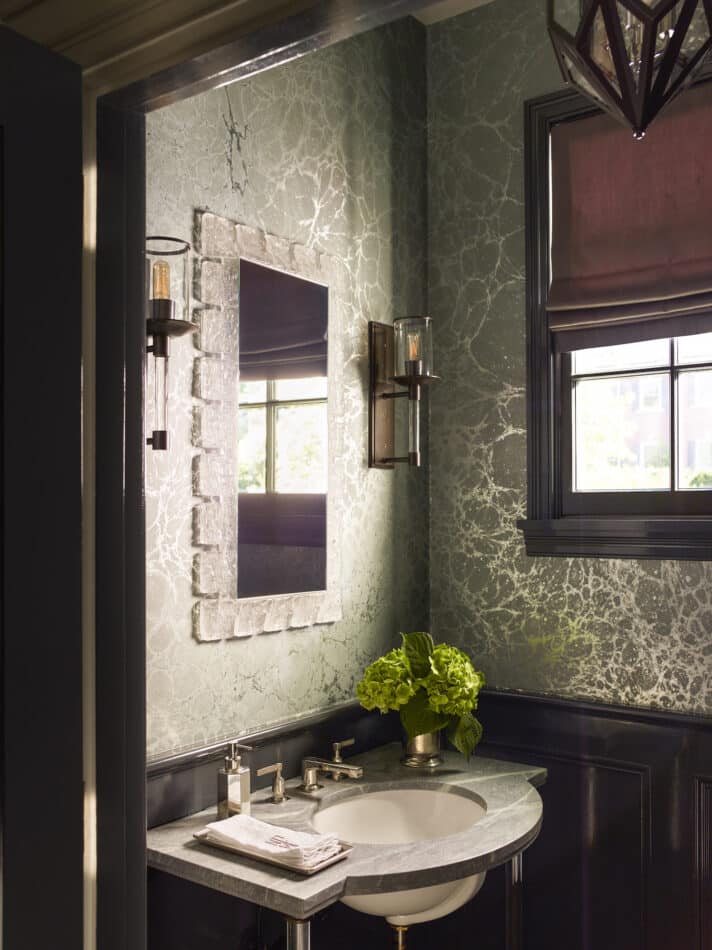 dark powder room with metallic wallpaper and a marble sink