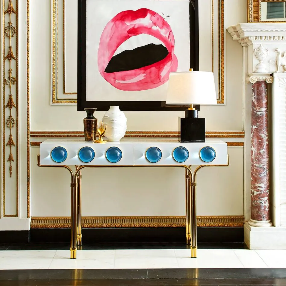  A Globo console table by Jonathan Adler with a white tabletop, brass legs, and light blue globes adorning the front. 