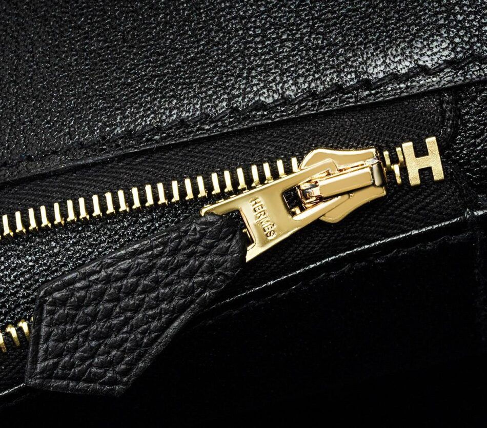 Close up of gold zipper on black Hermes Birkin bag.