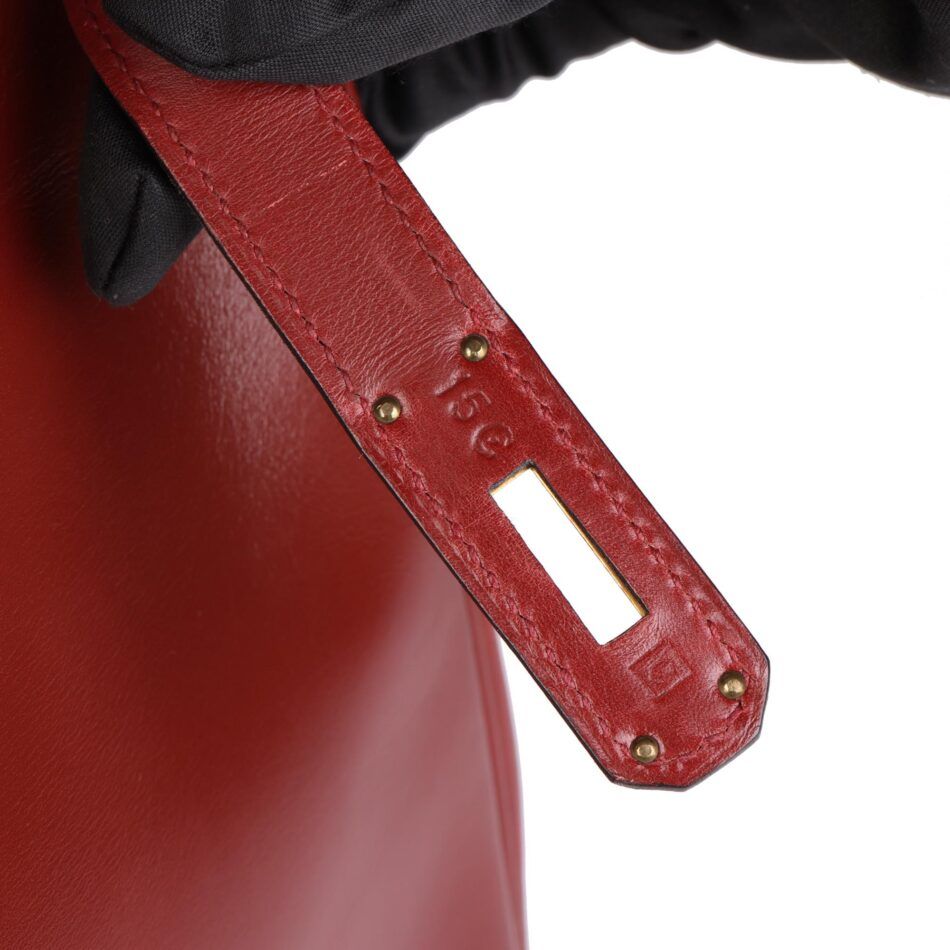 Close-up of the blind stamp on a red Hermes Birkin bag.