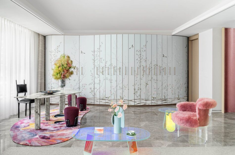 an all-white space with concrete floors and pink, fuzzy furniture
