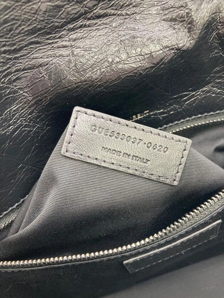 A close-up of a black serial number tag inside an authentic leather YSL bag.