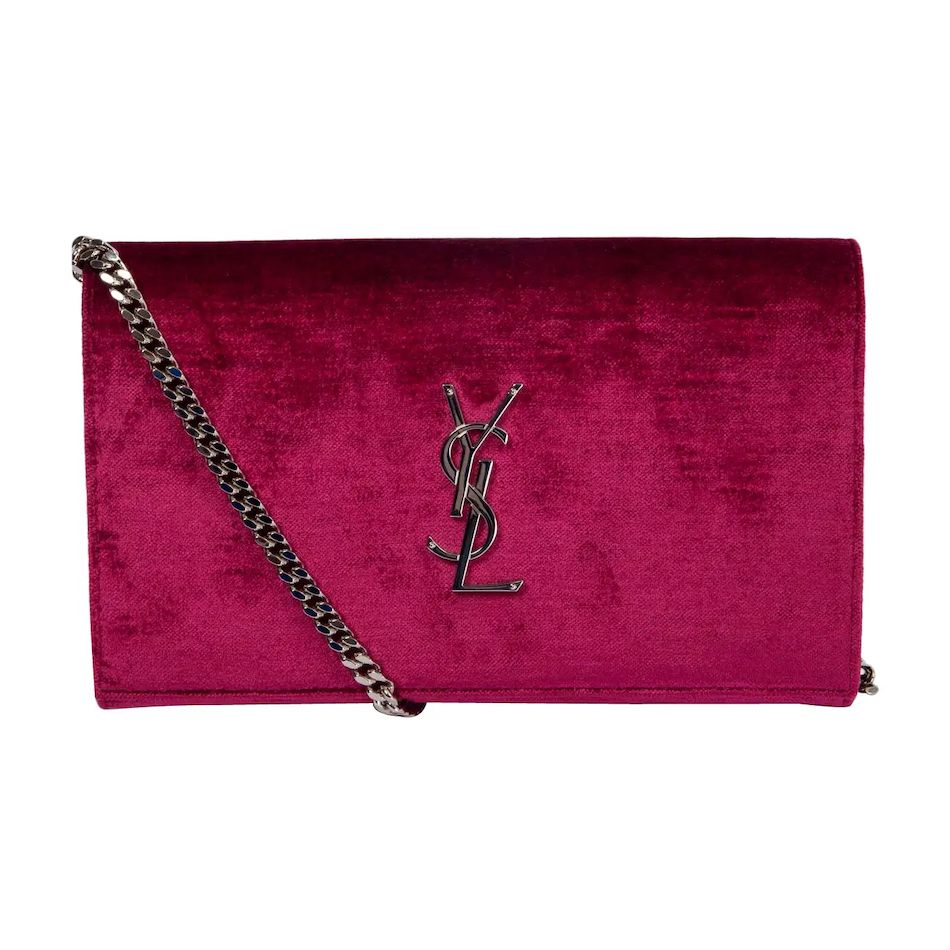 A YSL Kate Chain Wallet in fuschia velvet with a silver monogram in the center and matching chain draped across the front.