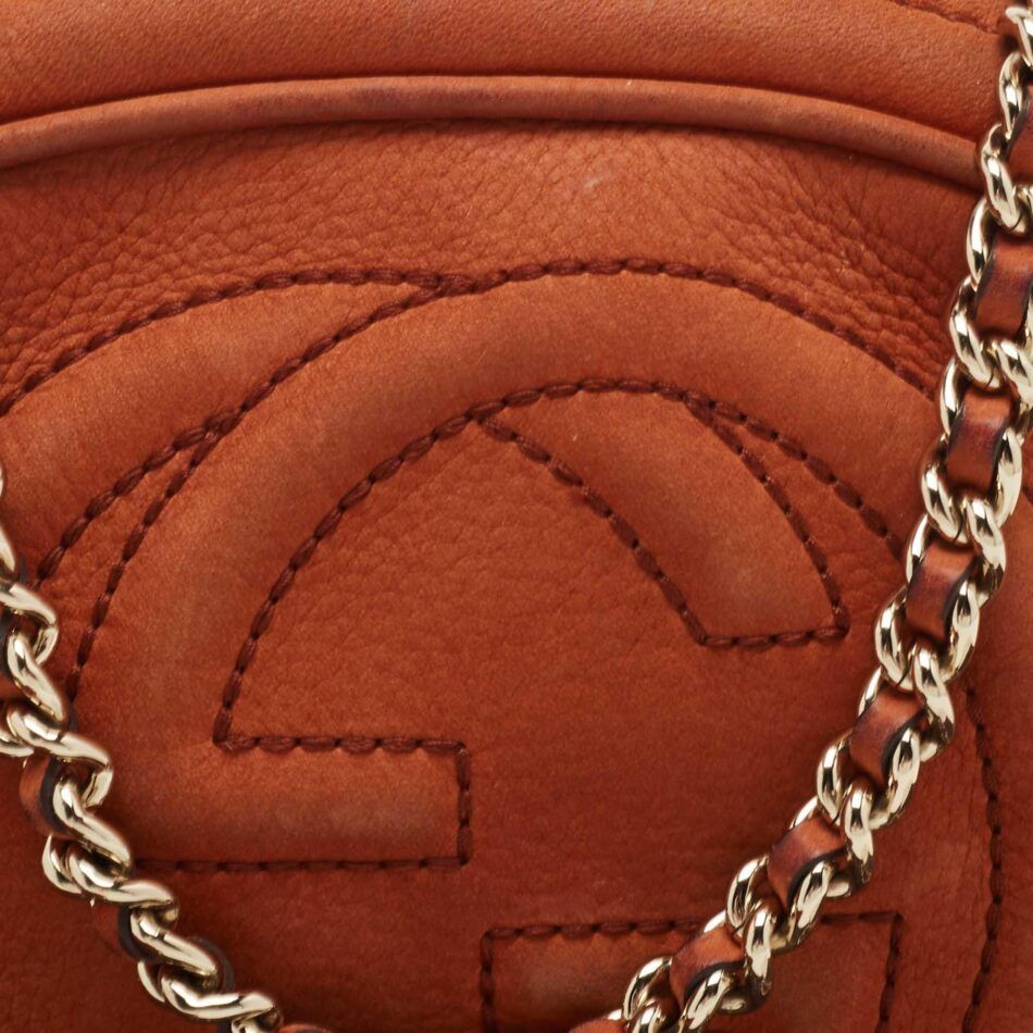 A close-up of the stitching on the interlocking G logo of a Gucci Mini Soho bag made from brown nubuck