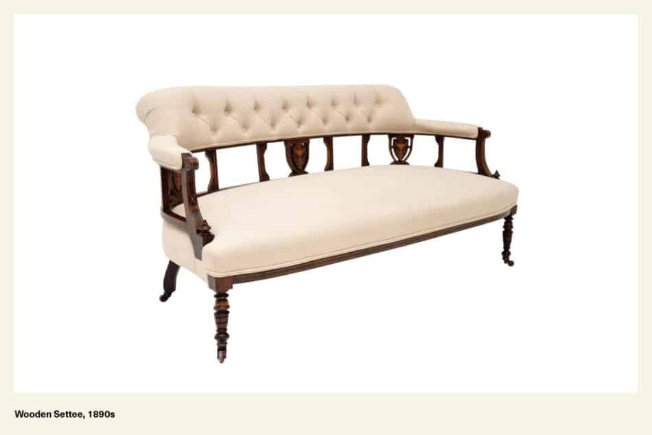 A Victorian wooden settee from the 1890s with cream-colored upholstery