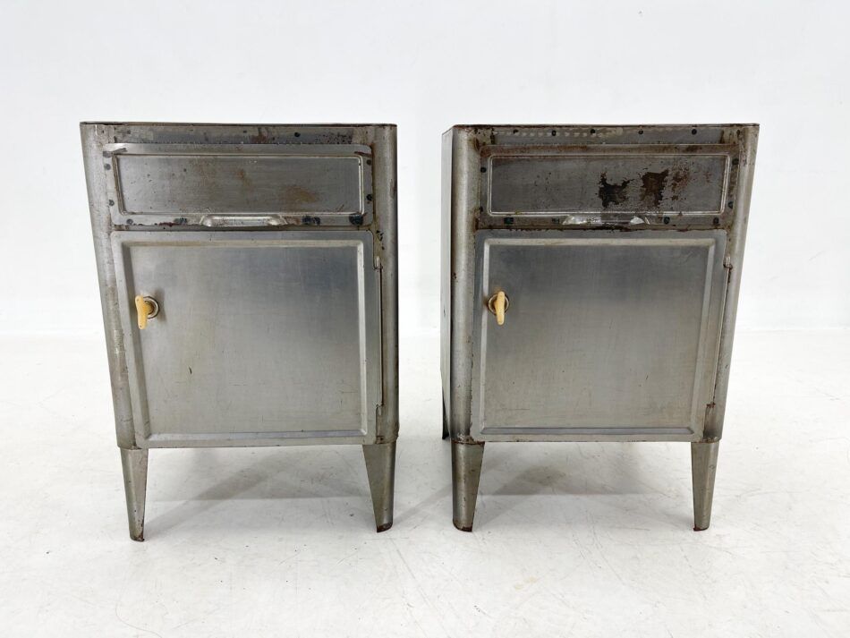 Two aged steel nightstands from the 1920s stand beside each other against a white background. 